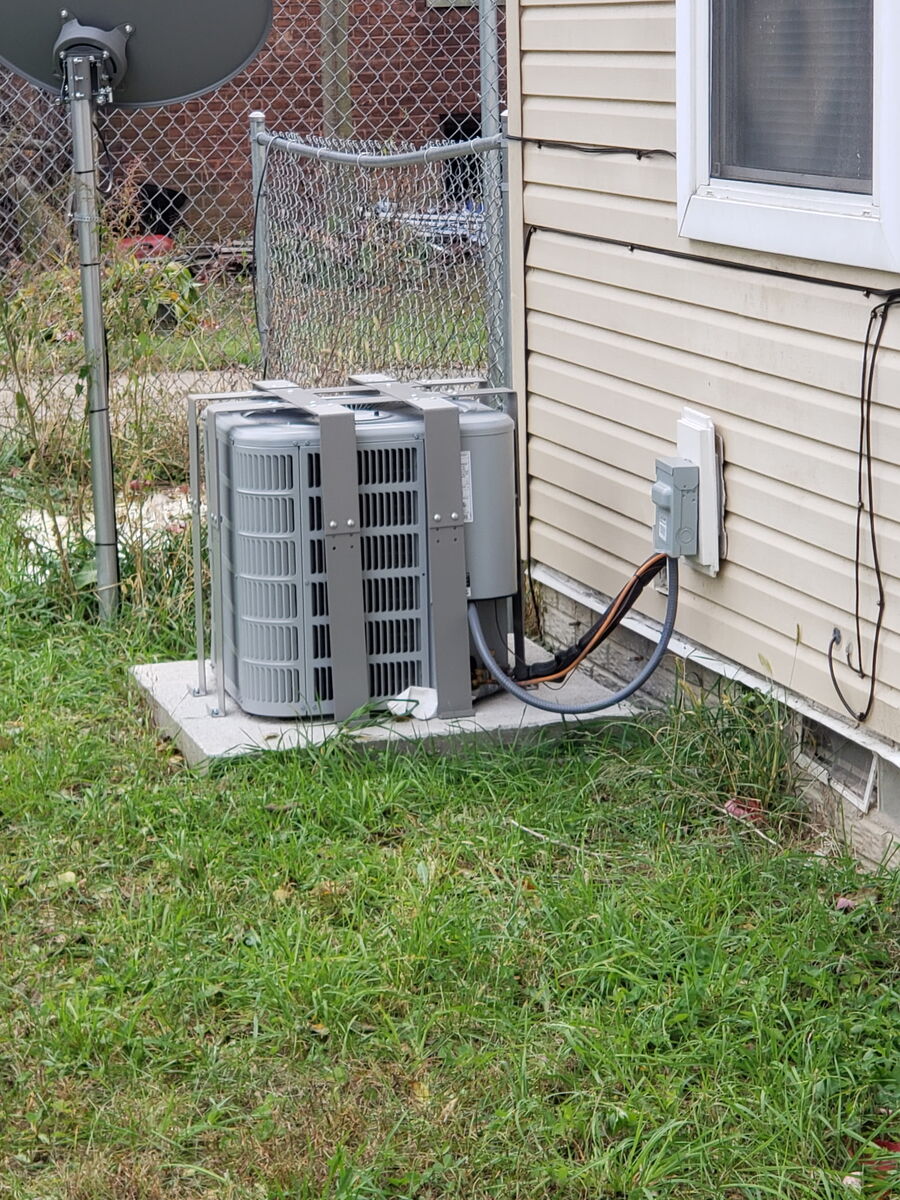 AC Bandit cage installed on a condenser beside a home's vinyl siding